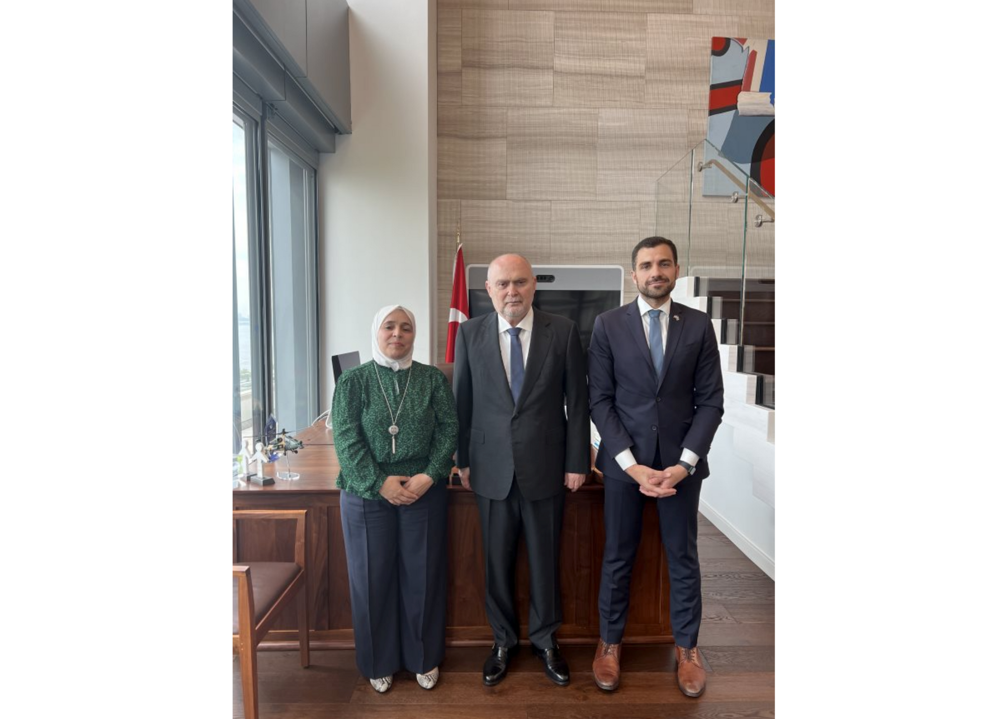 A woman stands next to two men in an office. 