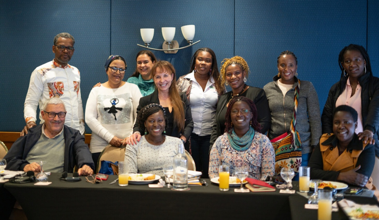 A group of people in two rows stand together and smile for a picture.