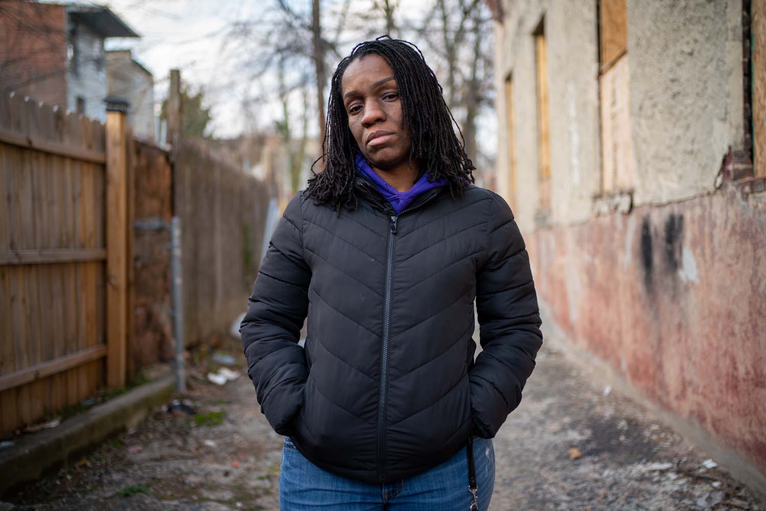 A young woman stands in an alleyway in a city, posing for a picture.