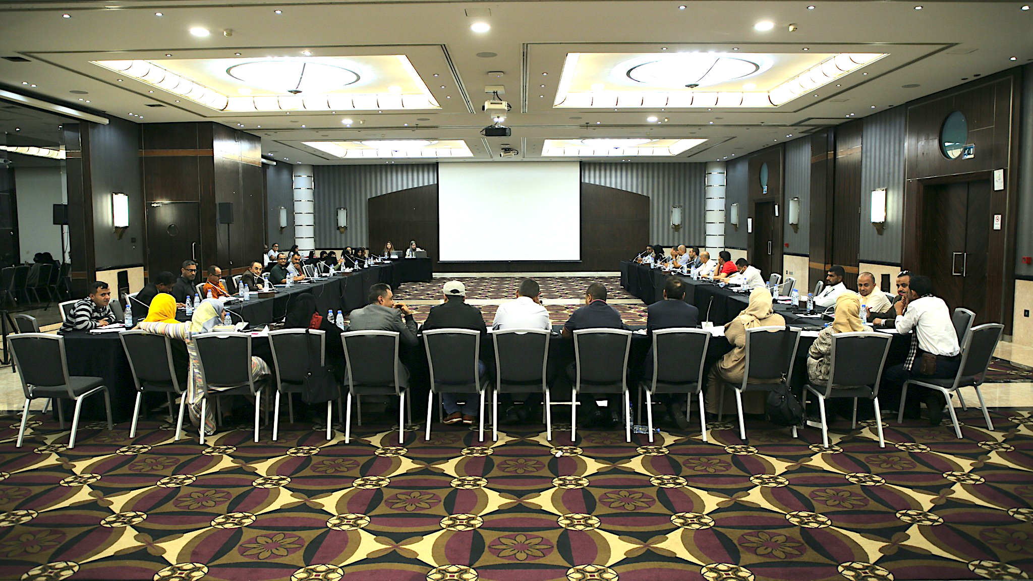 Les participants à l'atelier sont assis à une table de conférence, dos à la caméra.