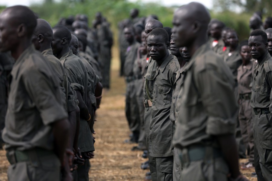 Men stand in ordered rows in military uniforms, with one man breaking ranks to gaze at the camera