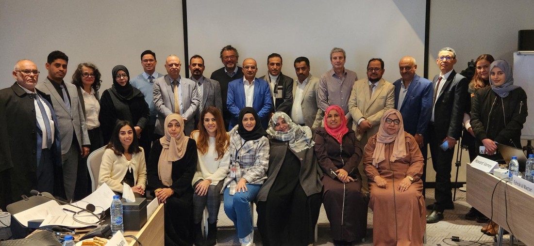 A group of people sit together for a photo in a conference room.