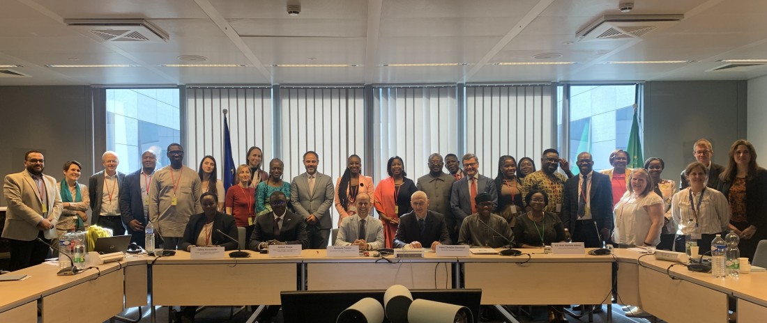 A group of people stand behind a long conference table and pose for a photo.