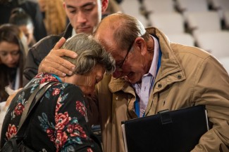 A man and woman embrace, touching foreheads. 