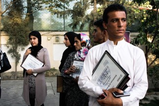 Youths stand around outside holding certificates