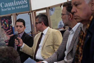 Former guerrilla member Gabriel Ángel holds the microphone for former paramilitary member Nodier Giraldo during an event at the Truth Commission.