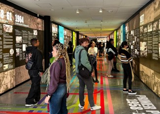 Several people walk through a room looking at various displays as part of an exhibition. 