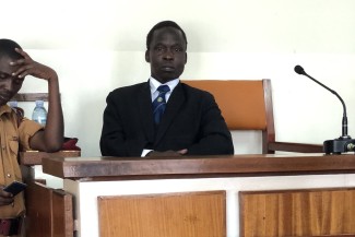 A man sits at a witness stand in a court room